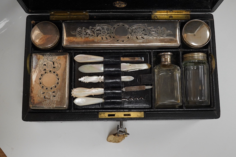 A Victorian leather vanity case with fitted interior to include white metal mounted glass bottles and mother of pearl mounted implements, with key, 27.5cm wide. Condition - fair, handle broken